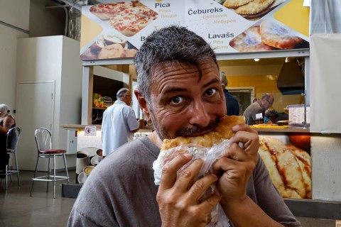Man enjoying cheburek in the lively Central Market of Riga, Riga, Latvia