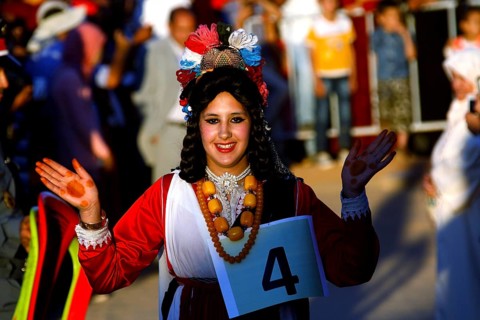 Smiling woman in traditional dress taking part in the Fête des Roses, El Kelâa m'Gouna,