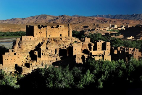 Clay buildings of the Kasbah in the Valley of Roses with surrounding mountain landscape under blue