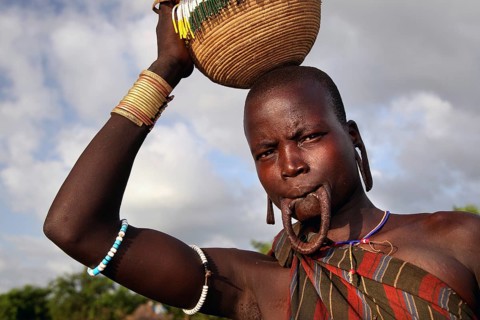 Morsi woman carries a basket on her head and has a lip plate in Mago National Park, Mago National