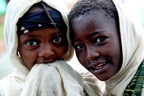 Two children wearing traditional clothes smile during a church service