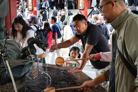 People purify themselves at a purification well in Senso-ji Temple, Tokyo, Japan