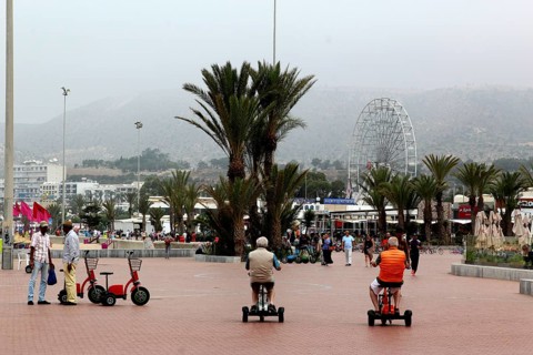 Visitors ride Segways along Agadir's beach promenade, palm trees line the trail, Agadir, Morocco