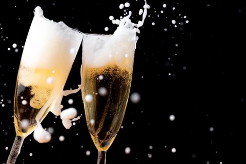 Two champagne glasses with sparkling and sparkling drink against a dark background