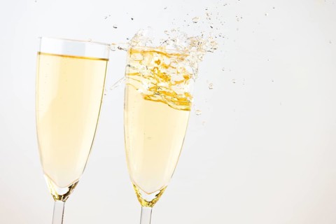 Two champagne glasses with sparkling drink against a bright background