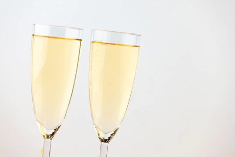 Two champagne glasses against a bright background