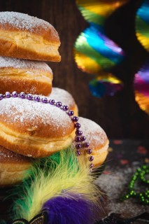 Close-up of Berliners with powdered sugar and pearl necklaces, colorful carnival atmosphere