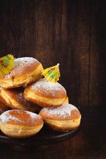 A pile of Berliners with powdered sugar on a dark wooden background, Mardi Gras
