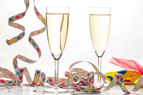 Two champagne glasses filled with colorful streamers, carnival