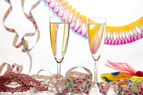 Two champagne glasses surrounded by decorative colorful streamers, carnival