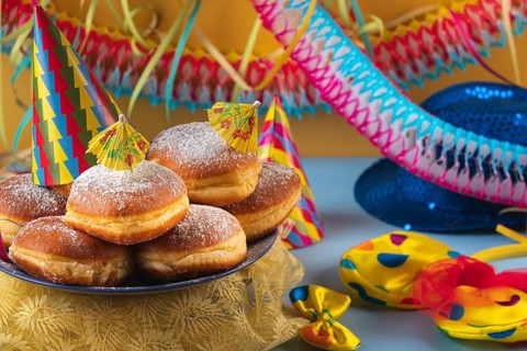 A plate of donuts decorated with party hats and colorful carnival accessories