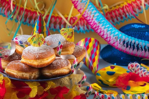 A plate of donuts surrounded by colorful party hats, streamers and garlands, carnival