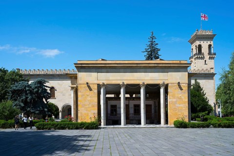 Historic building with columns and Georgian flag in clear blue sky, Josef Stalin Museum, Gori,