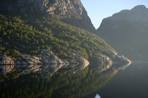 Pristine nature with wooded cliffs reflected in the tranquil Lysefjord, Lysefjord, Rogaland, Norway