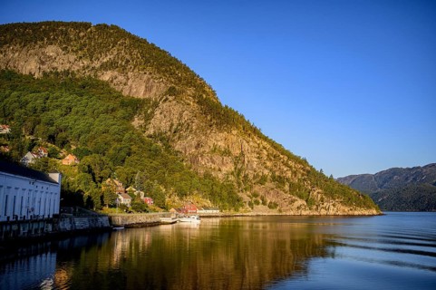 A peaceful stretch of Lysefjord with mountains and a picturesque village on the shore, view from