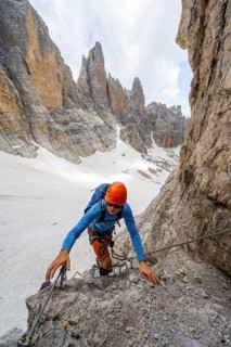 Mountaineer climbs on a steep rock face in the Via Ferrata dell'Ideale via ferrata, spectacular