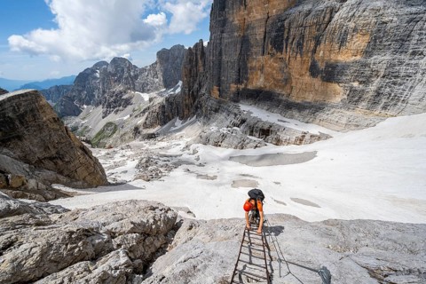 Mountaineer climbs on a ladder in the Via Ferrata Brentari via ferrata, spectacular mountain