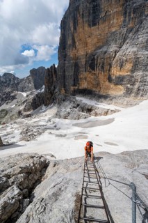 Mountaineer climbs on a ladder in the Via Ferrata Brentari via ferrata, spectacular mountain