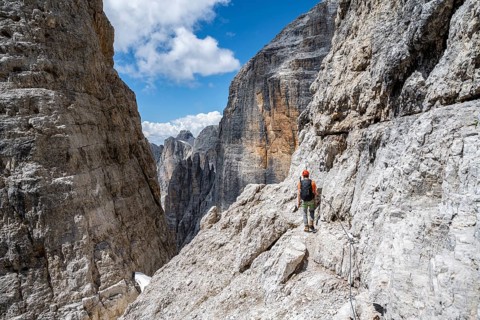 Climbers on the Via Ferrata Brentari via ferrata, spectacular mountain landscape with steep cliffs,