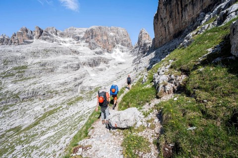 Three mountaineers on a hiking trail to Sella della Tosa, mountainous landscape in the Brenta