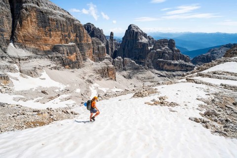 Female mountaineer in a snowfield on the Sella della Tosa, mountain landscape with steep cliffs,