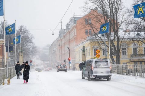 Pedestrians and cars on the snow-covered Auransilta bridge that crosses the Aurajoki River, wintery