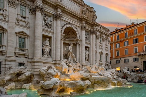 View at dusk at dusk with dramatic light in the sky of the partially illuminated Fontana di Trevi