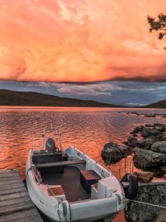 Boat moored on a jetty under a dramatic, colorful sky, Gutulia National Park, Engerdal, Innlandet,