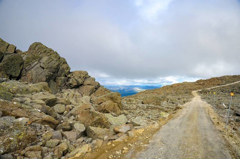Alvdal, Innlandet, Norway, Rocky road leads through a barren mountain landscape under cloudy sky,