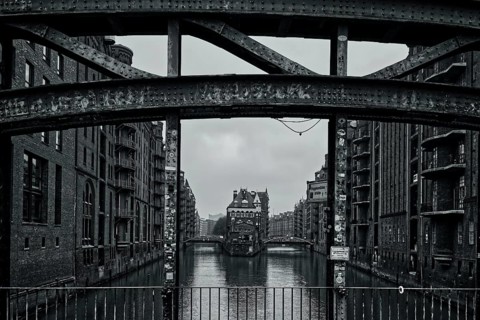 A black and white view of a bridge over a canal surrounded by historic buildings