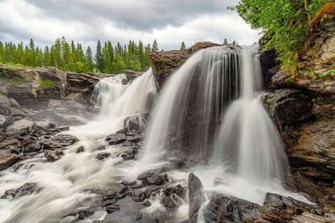 Mighty waterfall falling over rocky cliffs in a wooded area
