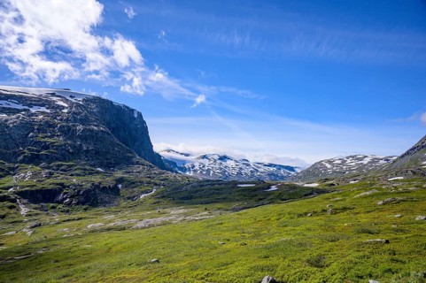 Geiranger, Møre og Romsdal province, Norway, green fields against snow-covered mountains under