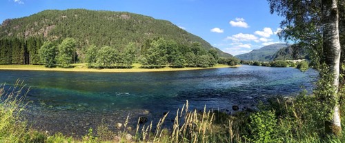 Sand, Rogaland Municipality, Norway, Clear river surrounded by green trees and meadows under a blue