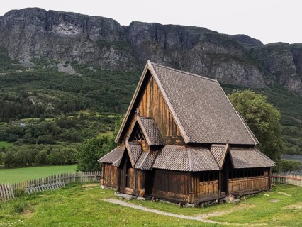 Øye, Innlandet, Norway, Traditional stave church in front of steep mountains in rural surroundings,