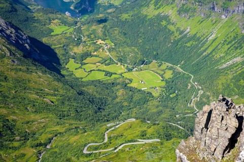 Geiranger, Møre og Romsdal Province, Norway, Winding road through green fields in a mountain valley