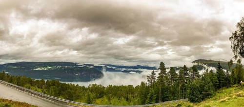 Utvik, Vestland, Norway, panoramic view of foggy mountain slopes and a dense forest under cloudy