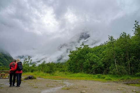 Fjærland, Vestland, Norway, couple looking at misty mountains surrounded by thick forest and a