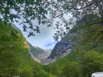Oldedalen, Vestland, Norway, view through trees of an impressive mountain gorge under a calm sky of