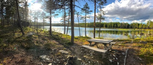 Storsjö Kapell, Jämtlands län, Sweden, panorama of a sunlit forest lake with picnic table in the