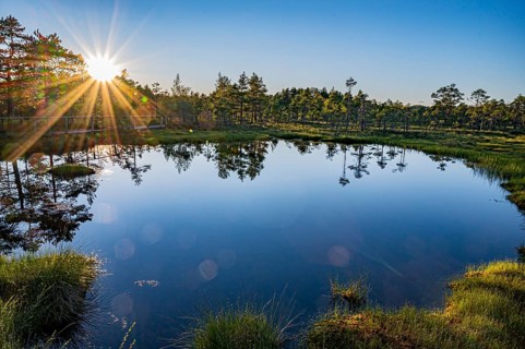 Hällefors, Örebro, Sweden, sunset over a lake with a clear reflection of the trees and a glowing