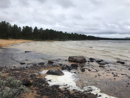 Drevsjø, Innlandet, Norway, A grey beach day with wavy water of Lake Femund, rocks and a thick