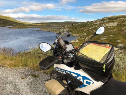 Haugastøl, Viken, Norway, A motorcycle with a map overlooks a quiet seascape in Hardangervidda