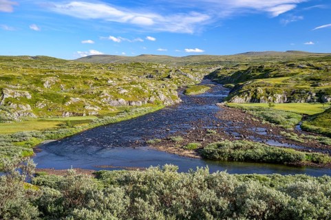 Vøringsfoss, Vestland, Norway, A wide river flows through a hilly, wild landscape under a blue sky