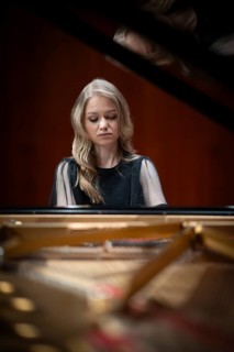 Young woman, pianist, with concentrated facial expression playing on a Steinway & Sons grand piano,