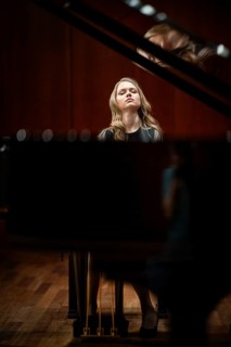 Young woman, pianist, with concentrated facial expression and closed eyes playing on a Steinway &