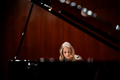 Young woman, pianist, with concentrated facial expression playing on a Steinway & Sons grand piano,