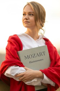 Self-confidently looking young woman, pianist, in white blouse and red cardigan, in the evening