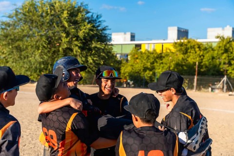 Young baseball players enjoying a moment of camaraderie and success, smiling and embracing after a