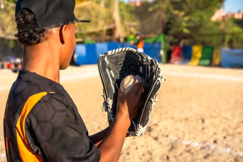 Young baseball player on a sunny field, focused with glove and ball, practicing pitching and