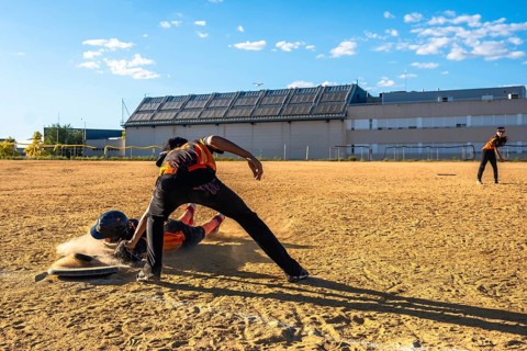 Baseball player sliding into home plate in a cloud of dust, attempting to score as the catcher